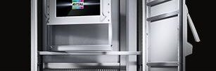 Tall metal safe with open door, showing internal shelves, electronic components, and a small display panel at the center of the cabinet.
