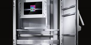 Tall metal safe with open door, showing internal shelves, electronic components, and a small display panel at the center of the cabinet.